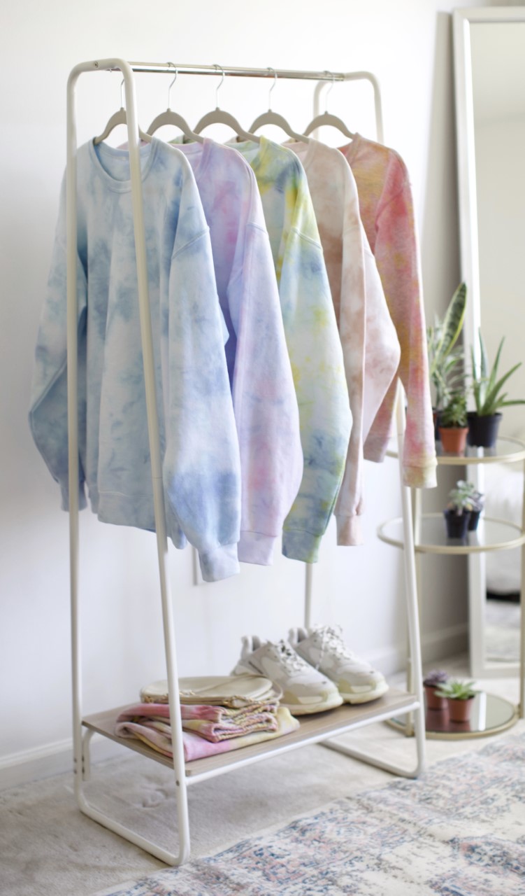 Five tie dye sweatshirts hanging on a standalone clothes rack