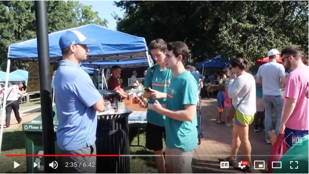 Two people speak to another person at the Davidson Farmers Market