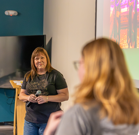 A presenter speaking with a microphone at a Hurt Hub event