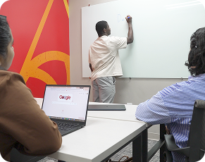 A student writing on a whiteboard while two others watch