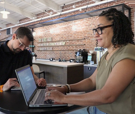 Two people working on laptops at the Hurt Hub coffee bar